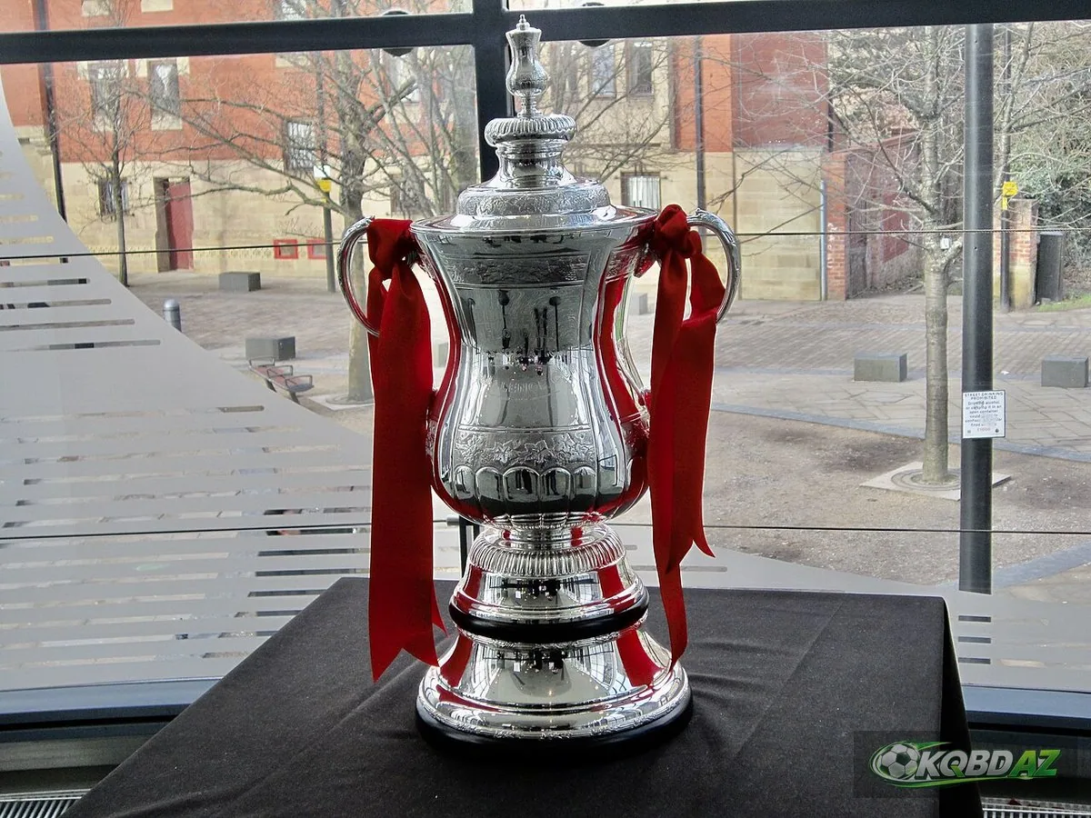 Chiếc cúp FA Cup bằng bạc với ruy băng đỏ trưng bày tại Bảo tàng Bóng đá Quốc gia Anh